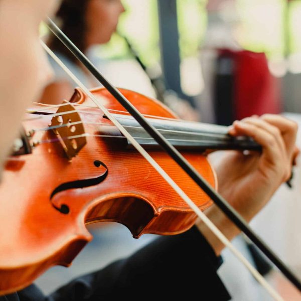 Back view of a violinist performing a piece with his violin, unfocused background